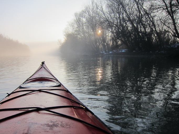 Red kayak in the foggy river. Winter kayaking in Danube river